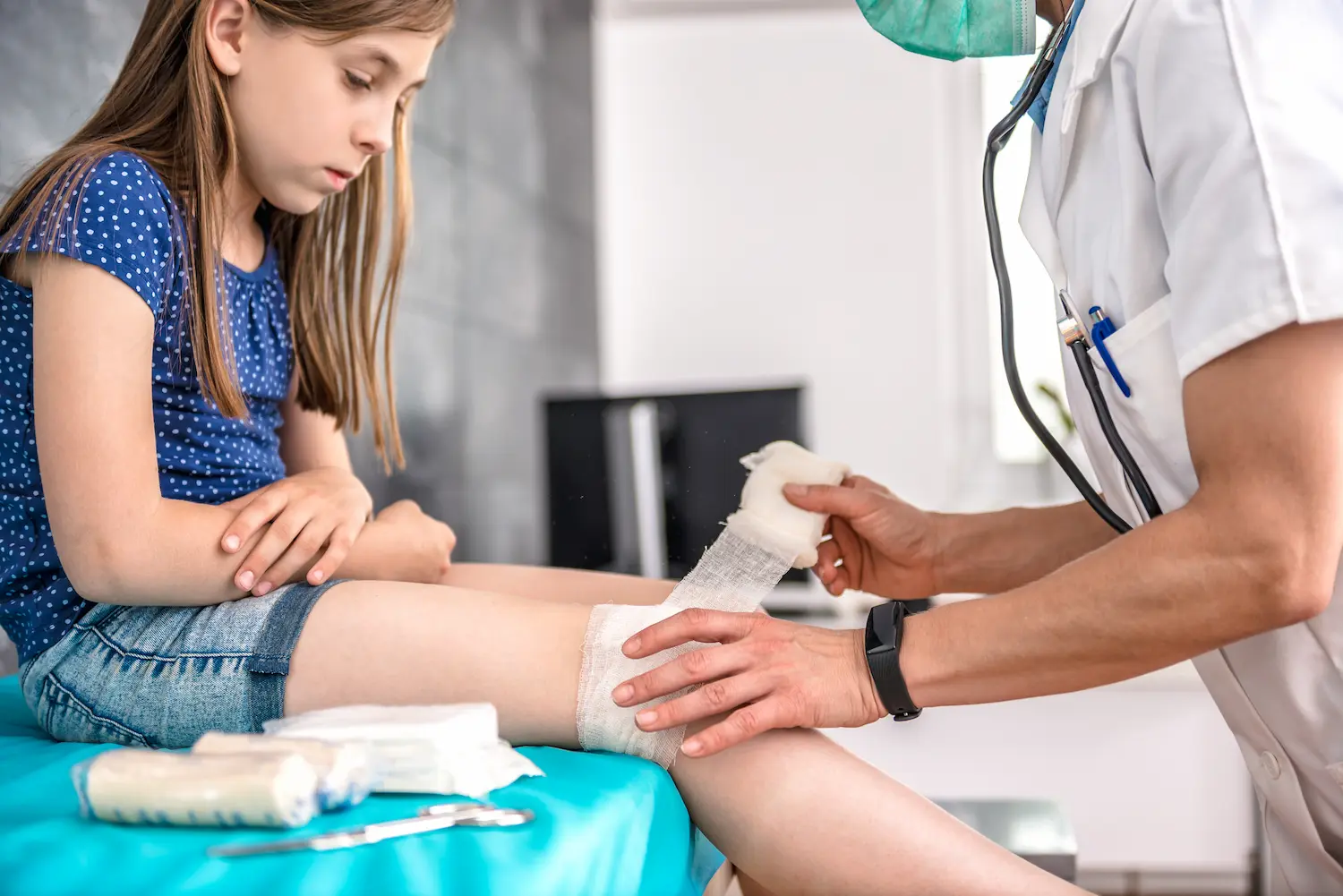 Fachgerechtes Wundmanagement bei Kind – medizinisches Personal versorgt eine Beinwunde mit steriler Kompresse und Verband.